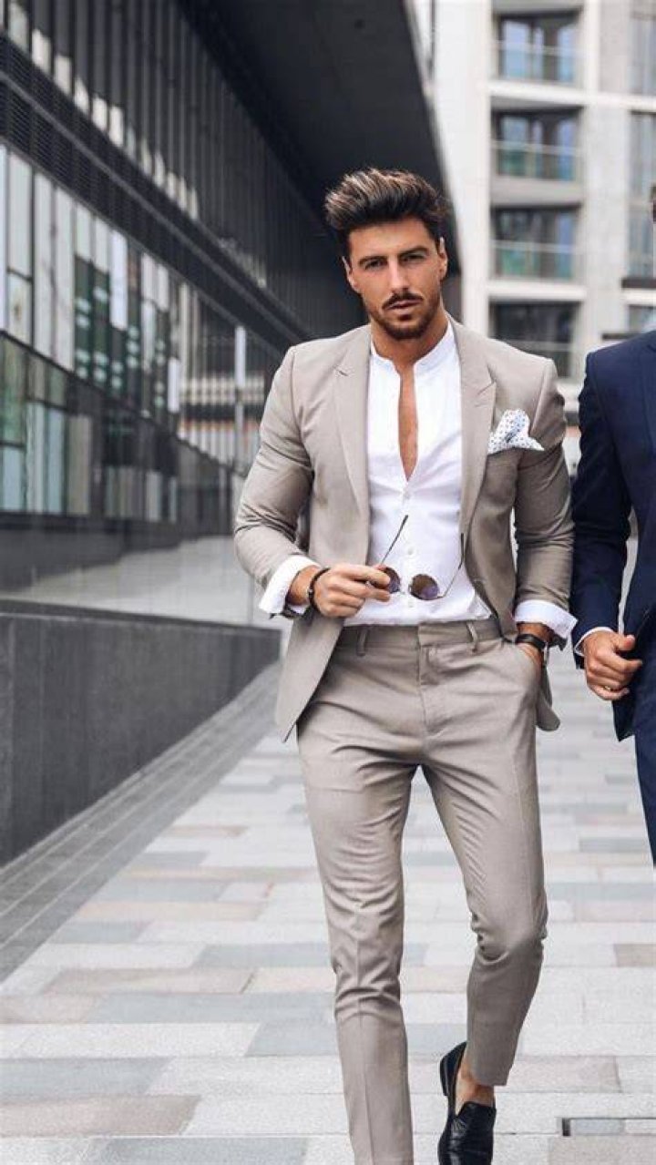 a man in a suit holding his hands on his chest and looking at the camera