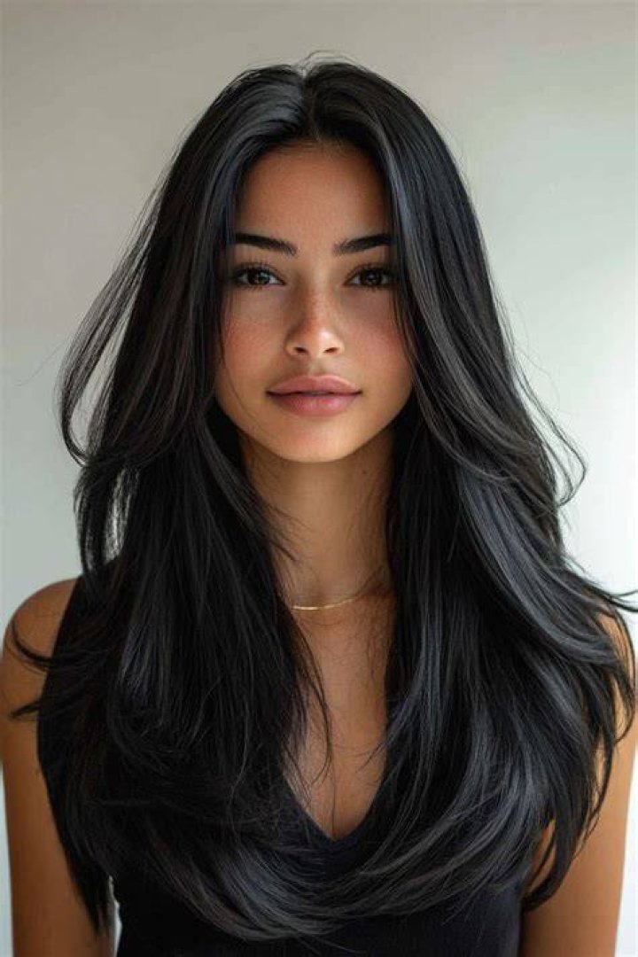 a woman with black hair is wearing a white collar and has her hand on