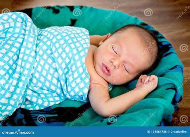 New Baby Boy Sleeping Wrapped in Fluffy Cream Blanket on Pathwork Quilt