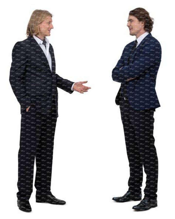 two men in suits standing next to each other on a red carpet at an event